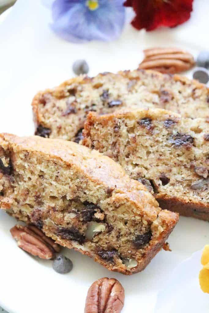 Vertical view of Sliced Banana Bread with pecans and chocolate Chips on a plate.