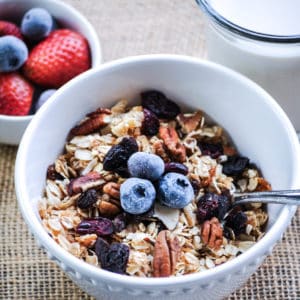 overhead shot of vegan granola in a white bowl with a garnish of blueberries