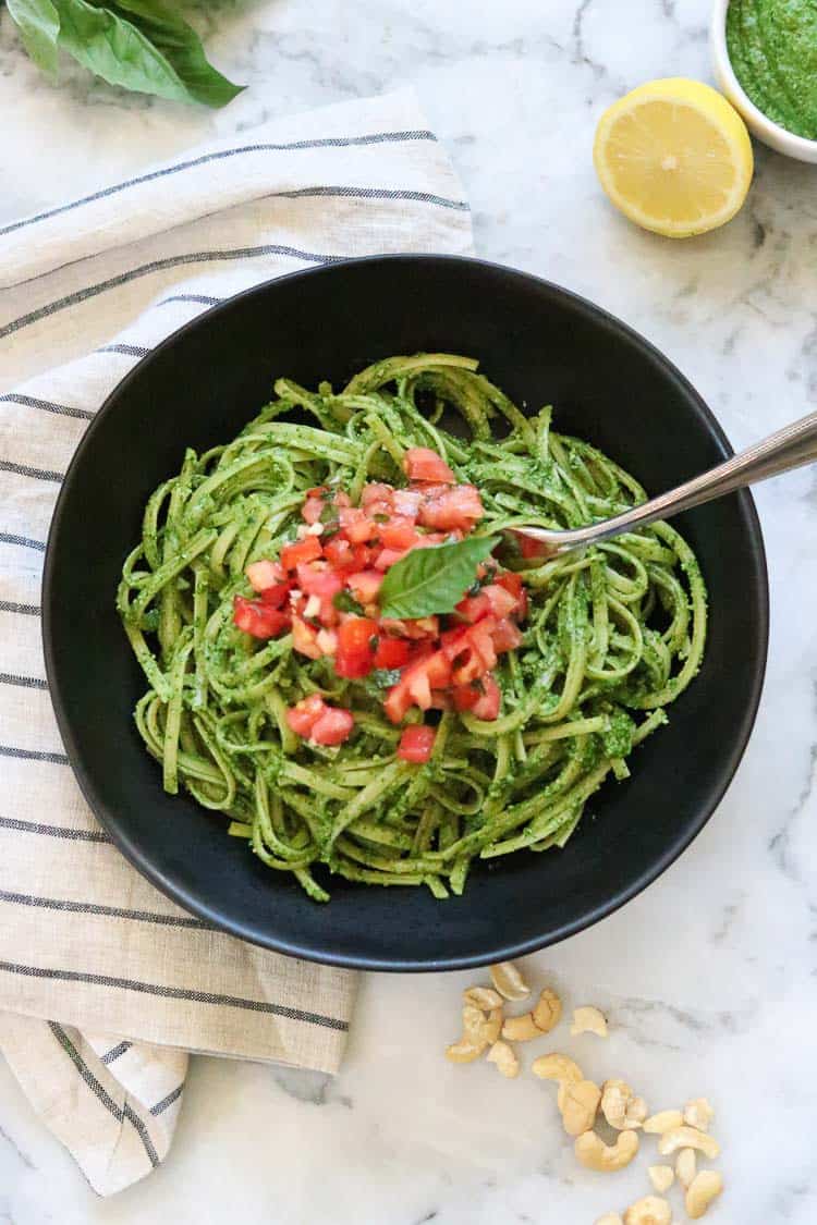 Vegan pesto on pasta with tomato bruschetta in the center.