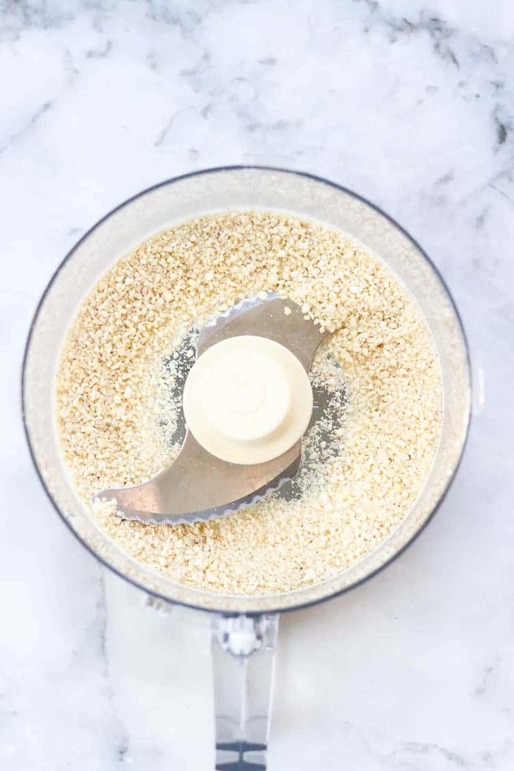 Cashew meal in a food processor as a Parmesan cheese substitute for vegan pesto.