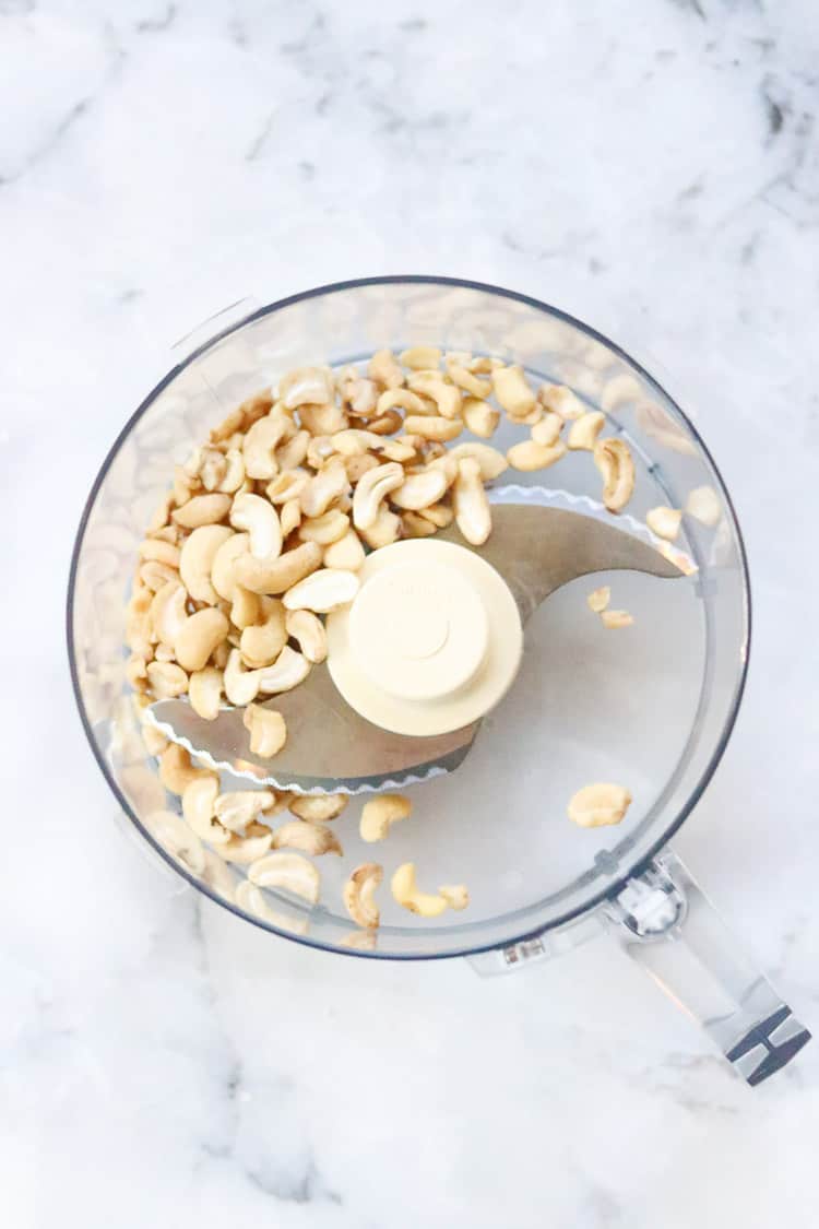 Cashew pieces in food processor bowl.