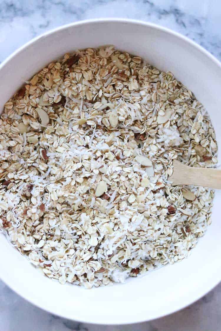 overhead shot of oats, nuts and coconut being mixed for vegan granola