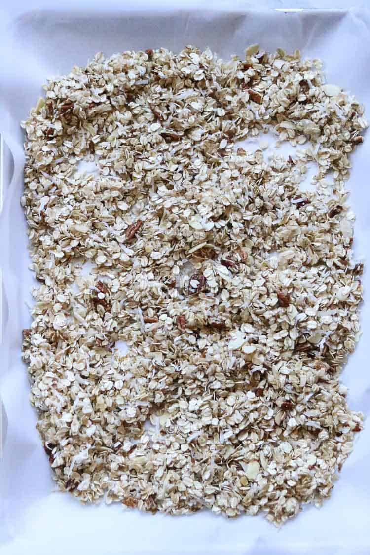 overhead shot of vegan granola on a parchment paper lined baking tray