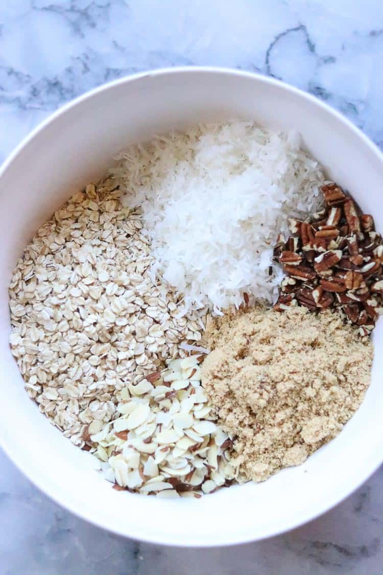 overhead shot of ingredients for vegan granola in white mixing bowl