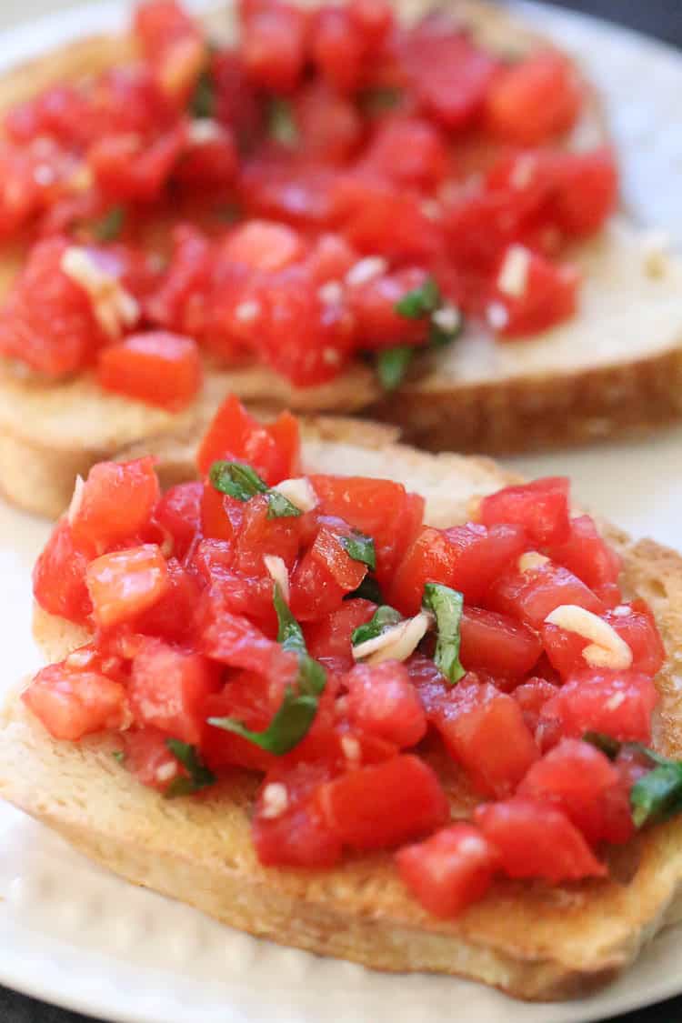 closeup side shot of of finely chopped tomato, garlic, and basil bruschetta on toasted french bread