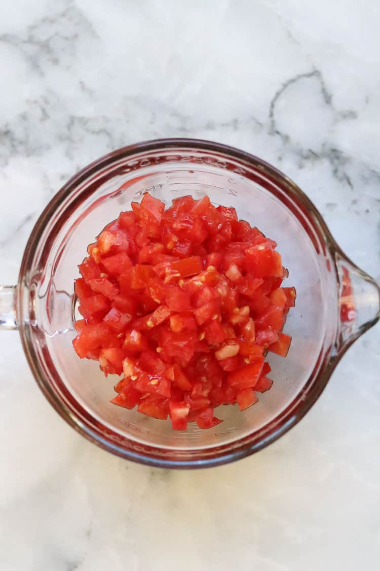 overhead shot of finely diced tomatoes in a large glass measuring bowl