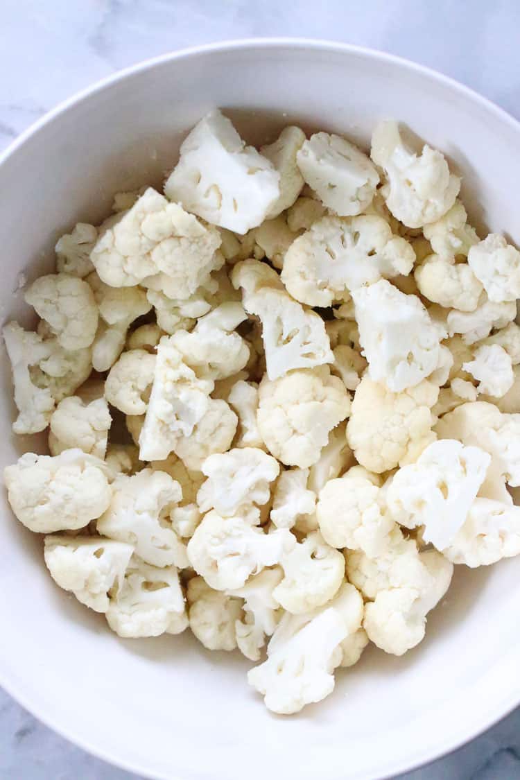 overhead shot of cauliflower florets in a white mixing bowl