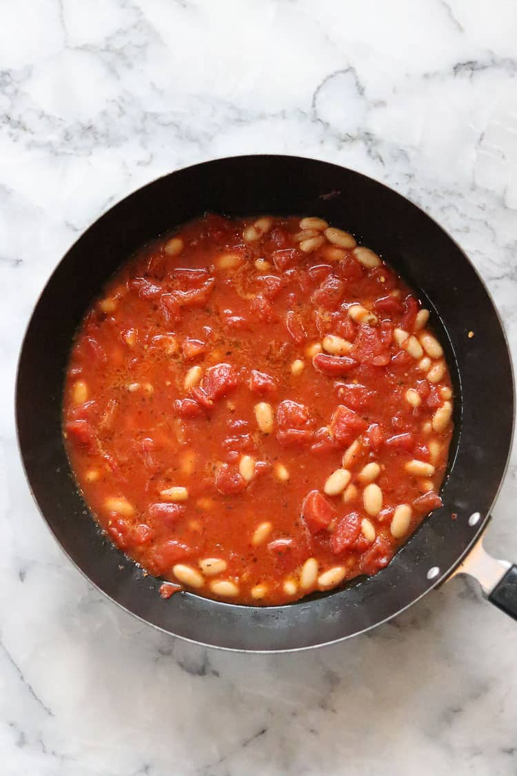 overhead shot of pasta sauce in black skillet with white Cannellini beans
