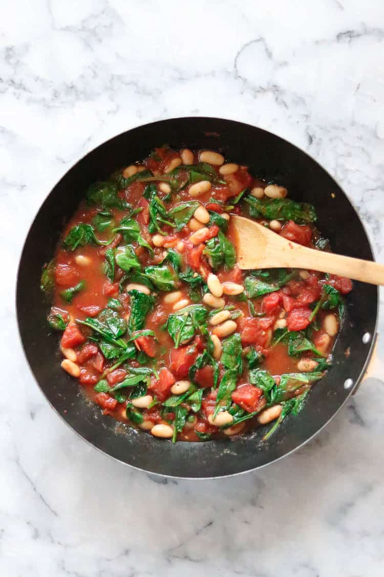 overhead shot of complete pasta sauce with wilted spinach in large skillet