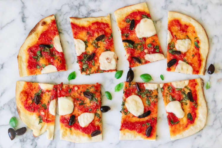 Overhead view of sliced vegan pizza with vegan mozzarella cheese melted on it 