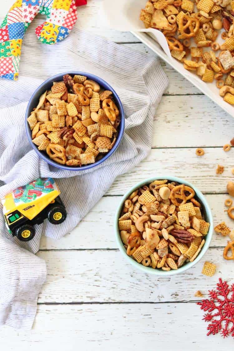 overhead shot of vegan Chex mix in bowls with ornaments and tray of mix nearby