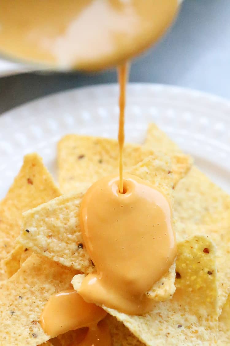 nacho cheese sauce being drizzled over tortilla chips