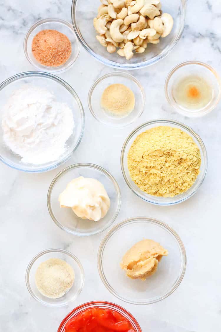 ingredients for cheese sauce in clear bowls with marble background