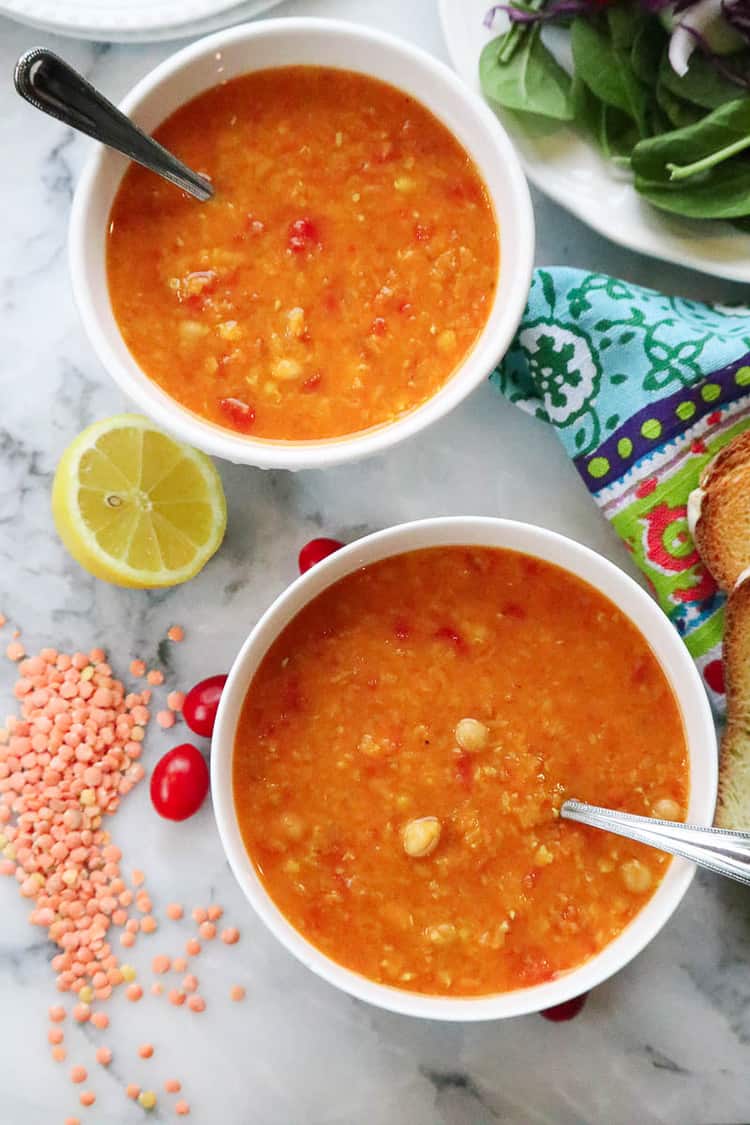 overhead shot of chickpea mediterranean lentil soup in two bowls with slice of lemon beside