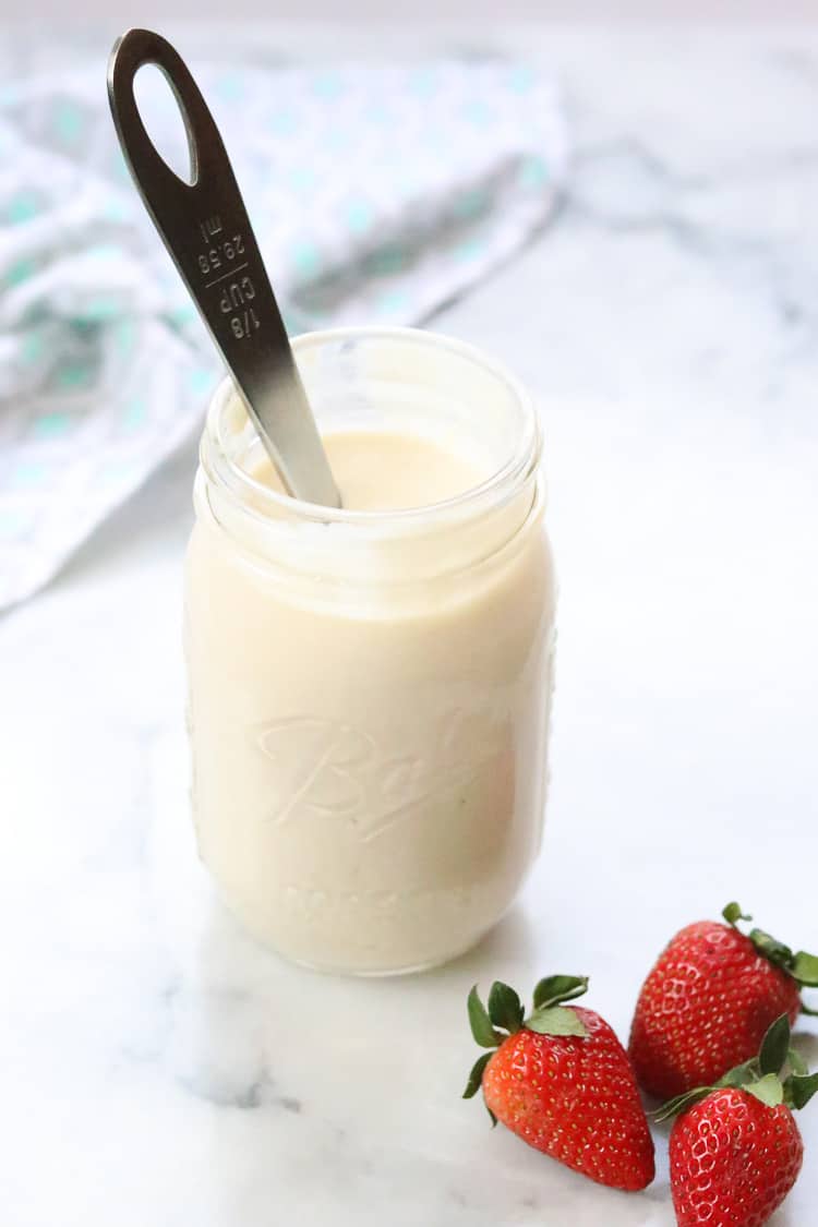 overhead side shot of vegan yogurt in pint jar with strawberries beside