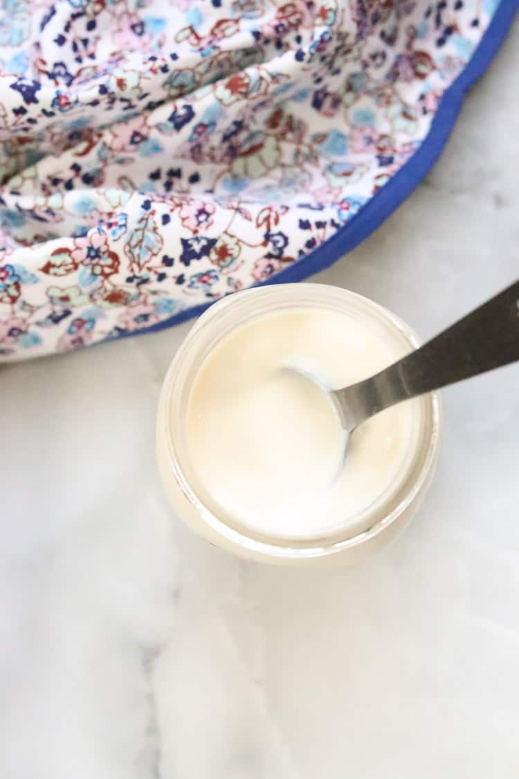 overhead shot of vegan yogurt in a jar with flowered tea towel beside 