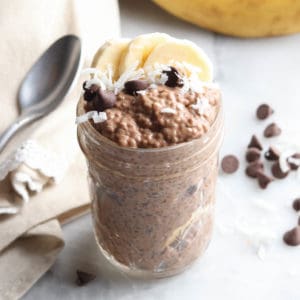 side overhead photo of chia pudding piled in pint jar and garnished with banana, coconut, and chocolate chips