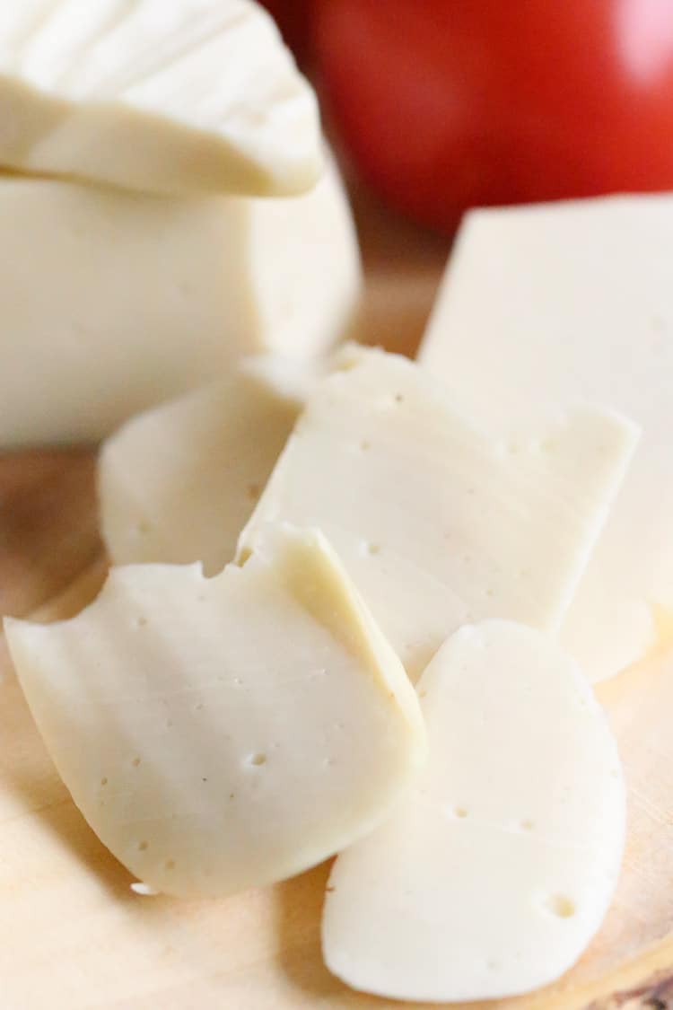 slices of vegan mozzarella cheese with cheese blocks in the background