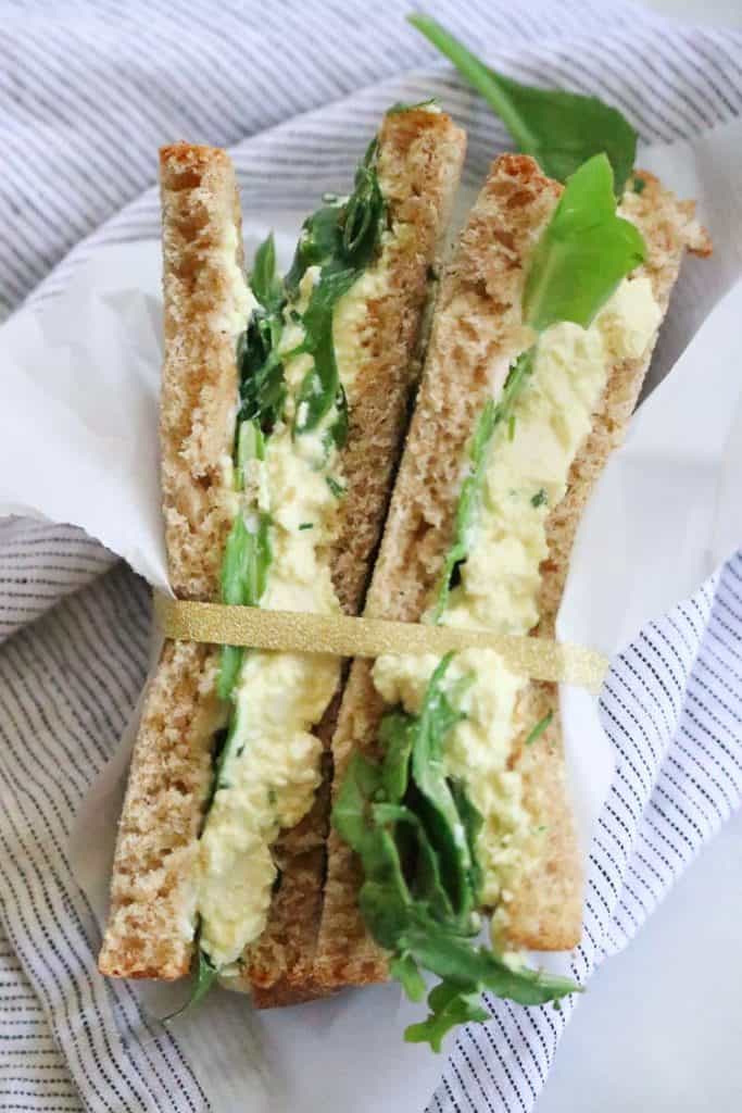 Sliced Vegan Egg salad sandwich turned on edge and bound together with golden ribbon.
