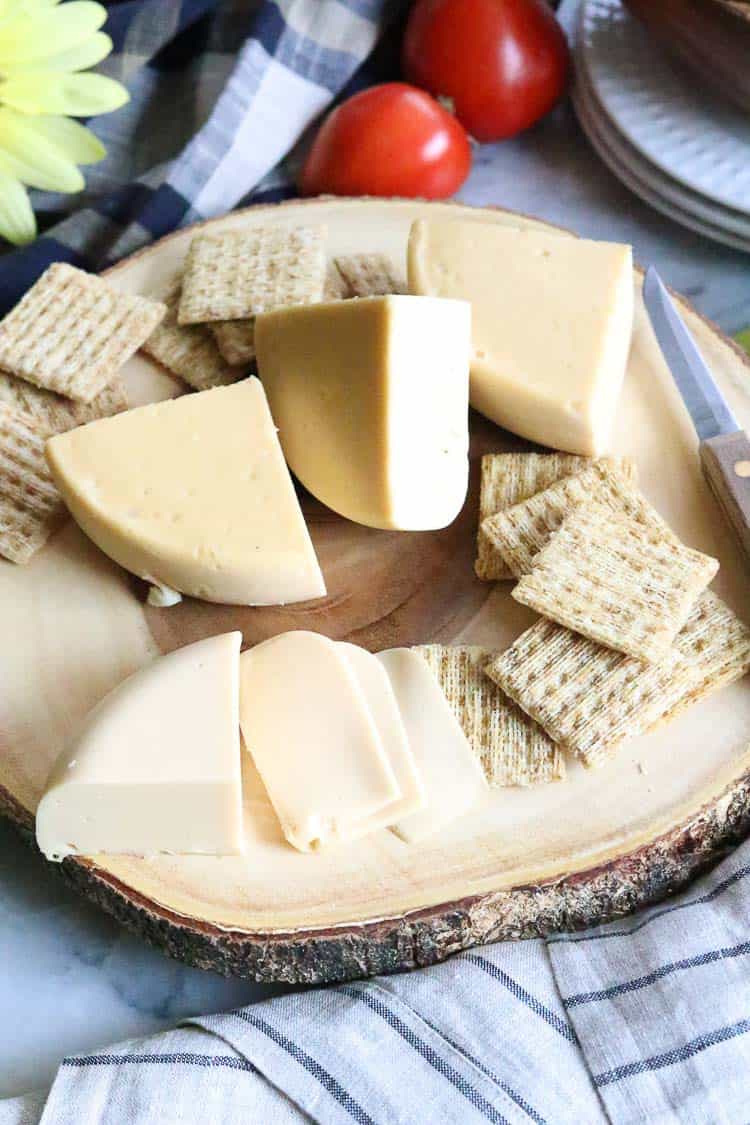 side overhead shot of vegan smoked gouda block cheese quartered and sliced with crackers 