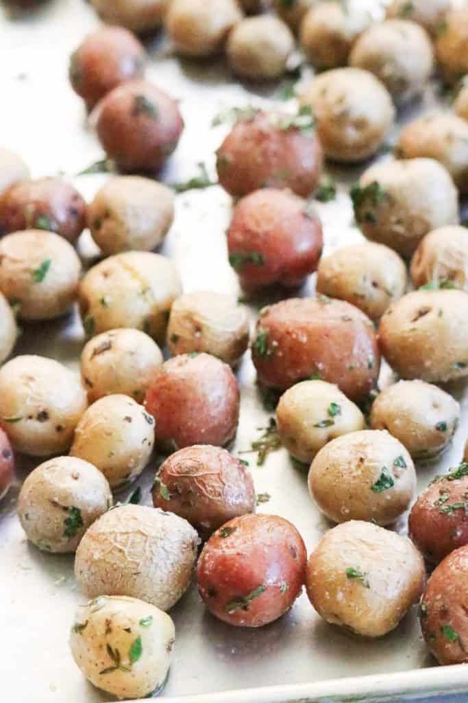 Red and white roasted baby potatoes on a silver baking tray.