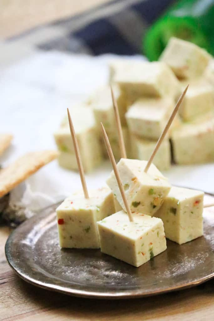 Cubes of Vegan Pepper Jack cheese on a coaster with toothpicks