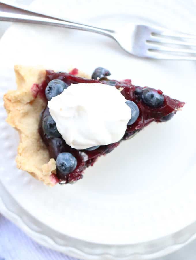 Overhead shot of Easy Blueberry pie on a plate with a dollop of whipped coconut cream.