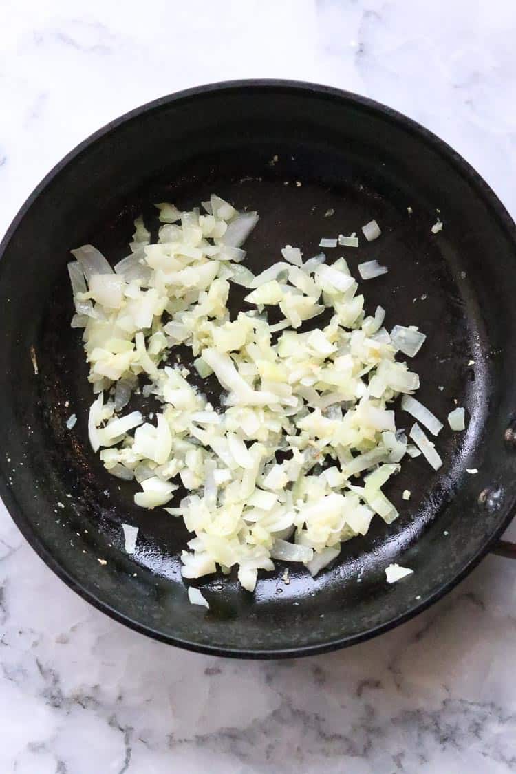 Sautéed garlic and onions in a black frying pan.