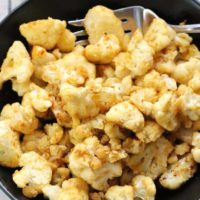 overhead shot of oven roasted cauliflower in a black serving dish with neutral napkin