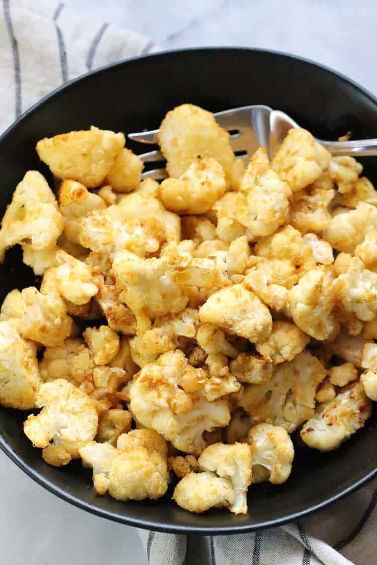 overhead shot of vegan baked cauliflower in a low wide black bowl