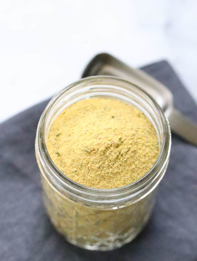 overhead shot of vegan chicken seasoning in a small clear jar with teaspoon beside
