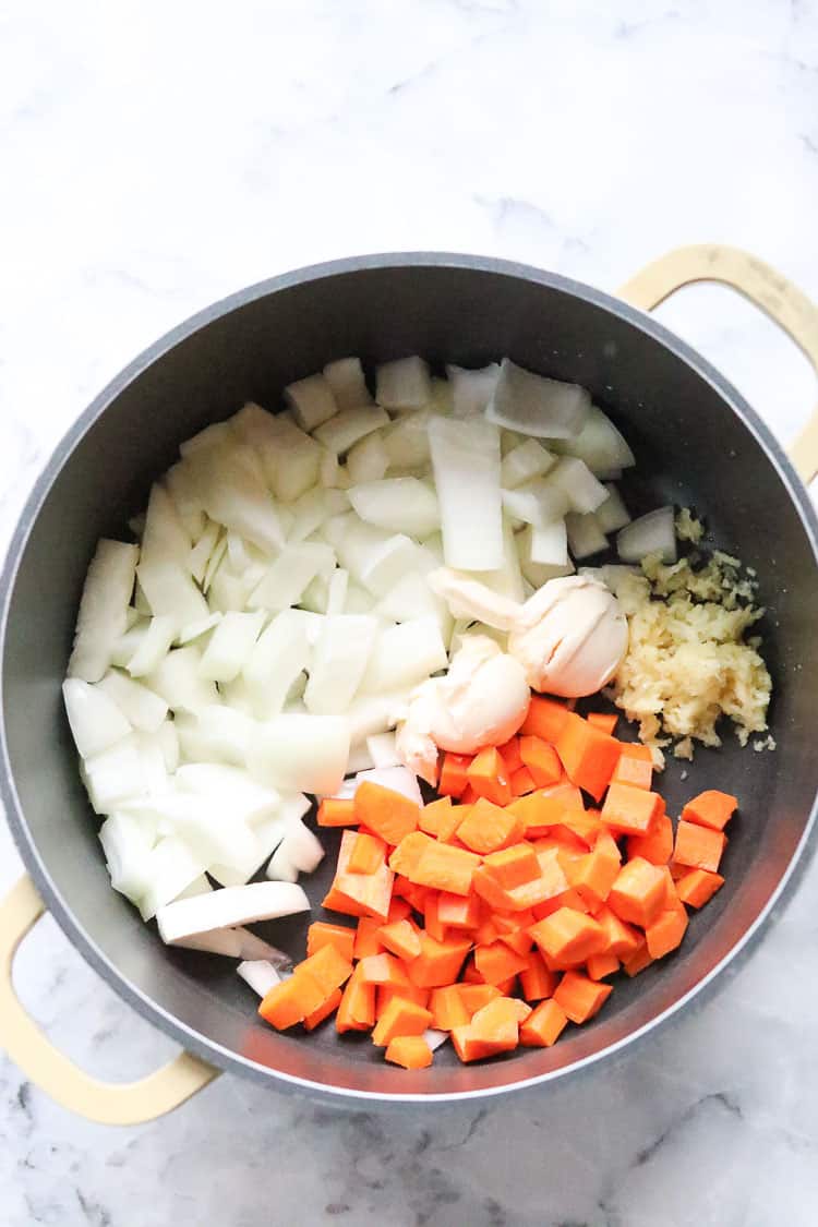 overhead shot of chopped onions, carrots, and minced garlic in a pot