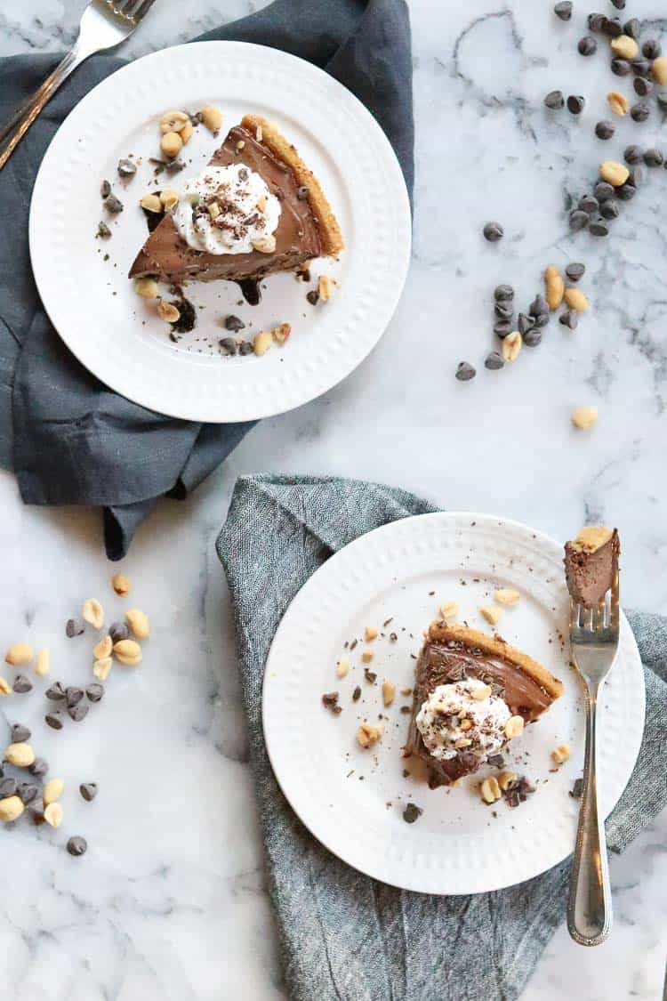 overhead shot of vegan peanut butter pie on two plates with whip cream and chocolate garnish