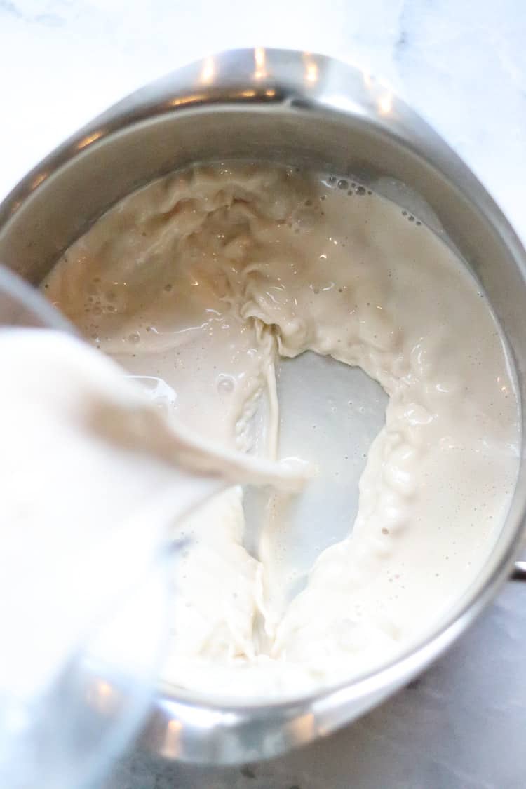 overhead shot of blender mixture for vegan gravy being poured into silver pot