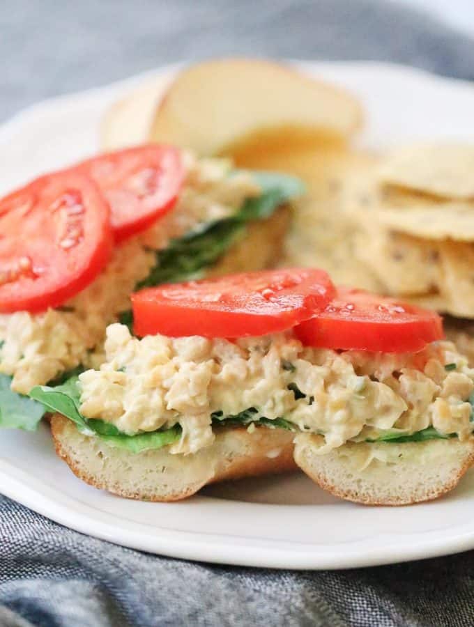side closeup shot of vegan chickpea salad on half a bagel with lettuce and tomato
