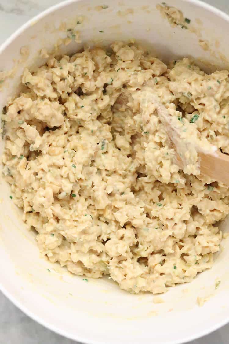 overhead shot of all ingredients for vegan chickpea salad being stirred together in a white bowl