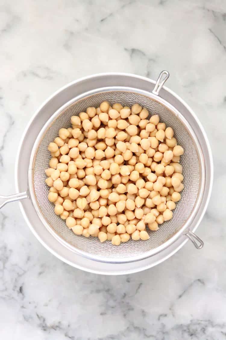 overhead shot of chickpeas in a strainer for vegan chickpea salad