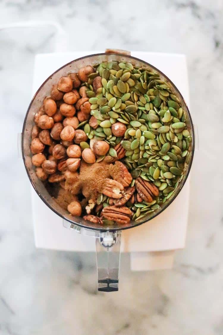 overhead view of nuts and seeds with spice mix in food processor bowl
