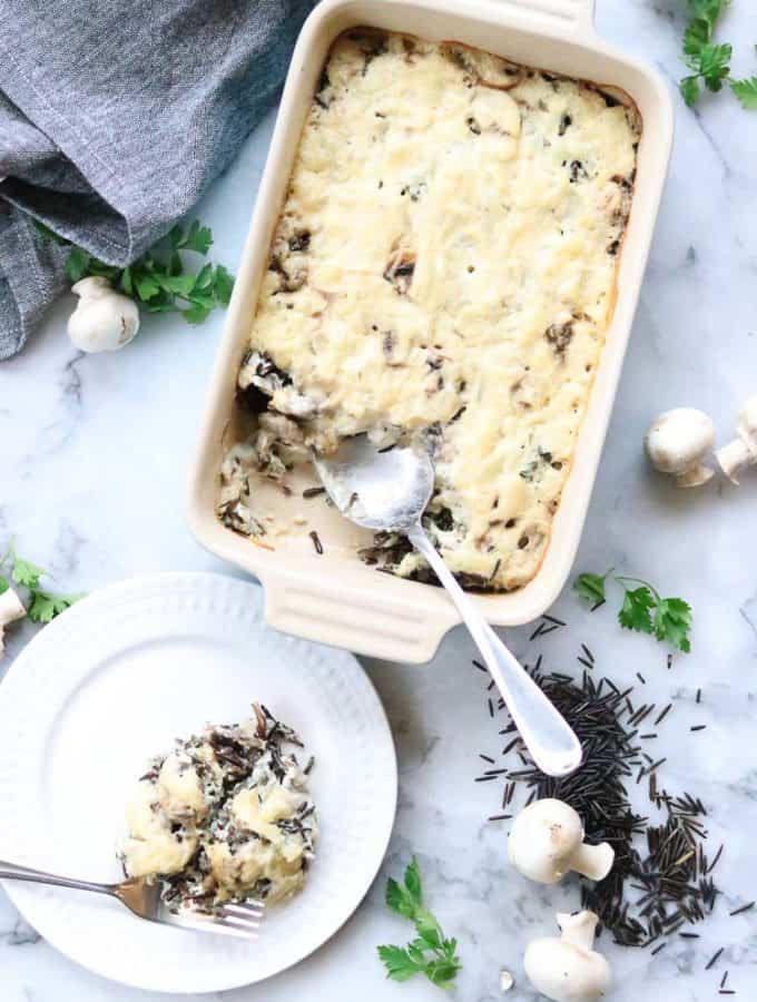 overhead shot of vegan wild rice casserole dish and separate serving on a small white plate