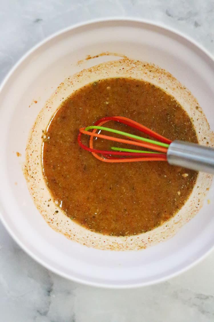 overhead shot of seasonings whisked together in white bowl for vegan tamale filling