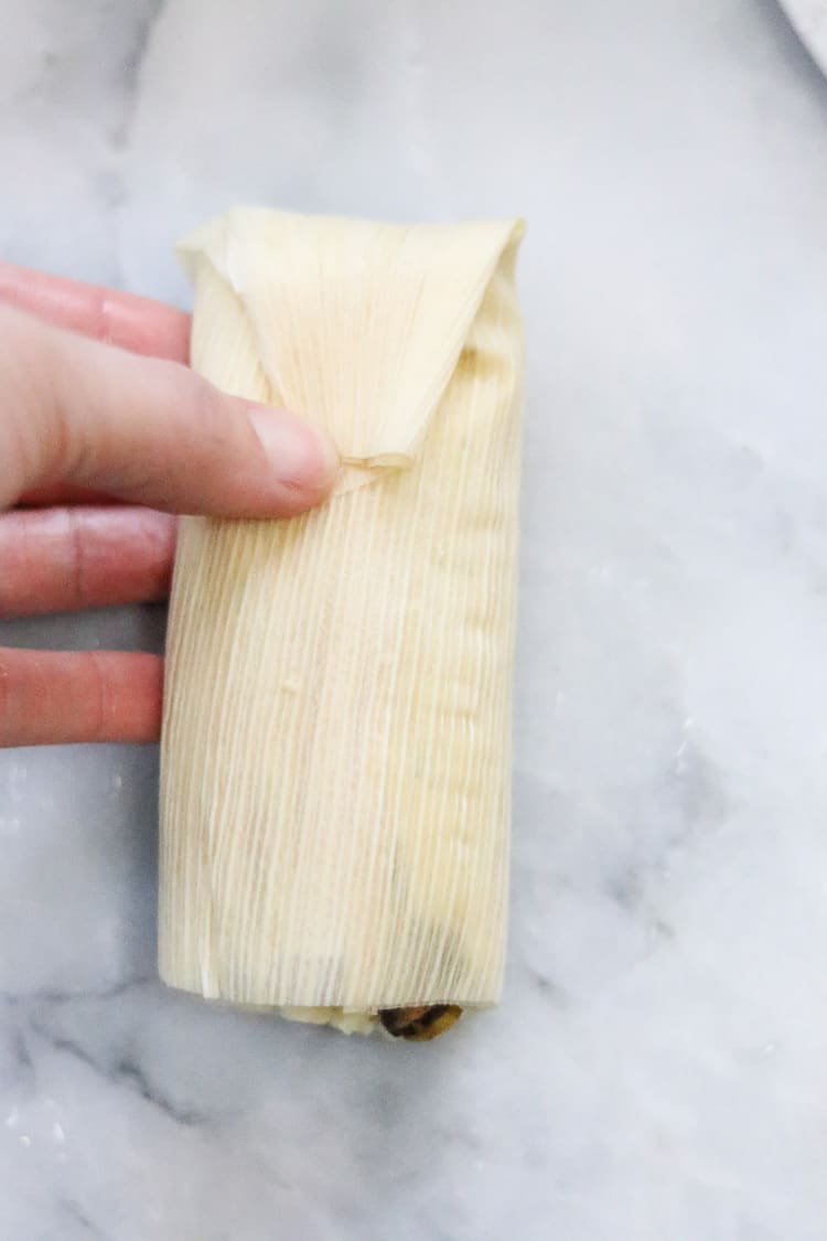overhead shot of tail of vegan tamale being folded down