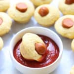side overhead shot of vegan corn dogs bites being dipped in ketchup ramekin
