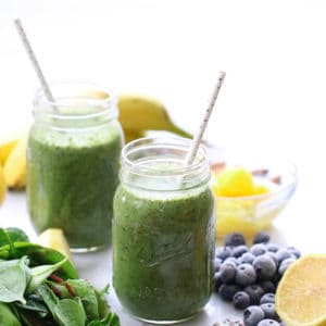 side overhead shot of vegan smoothie in mason jars with power greens and lemon nearby
