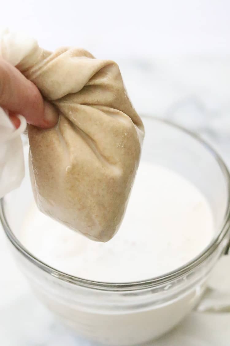 side overhead shot of nut milk bag being squeezed for oat milk