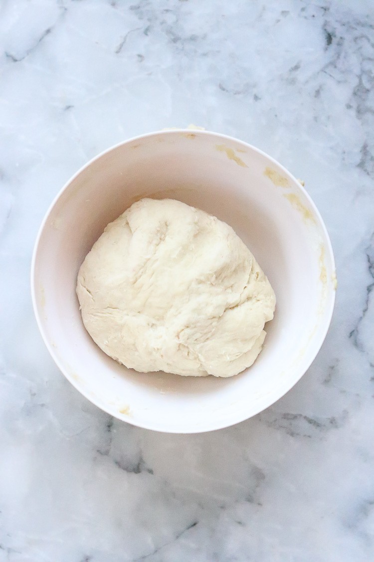overhead shot of vegan calzone dough in a large white bowl