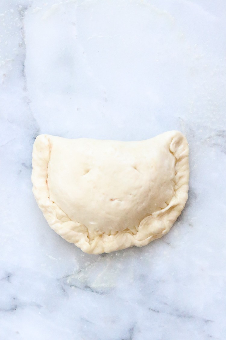 overhead shot of vegan calzone dough edges folded and pressed in