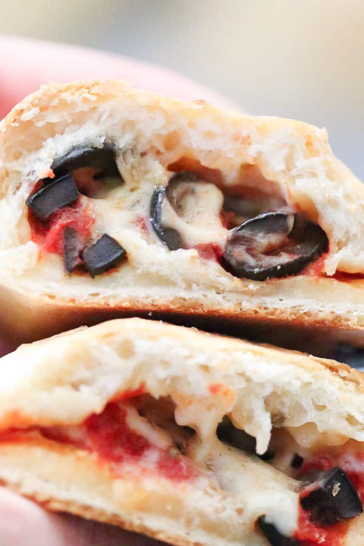 closeup overhead shot of halved vegan calzone showing melty cheese, sauce, and olives