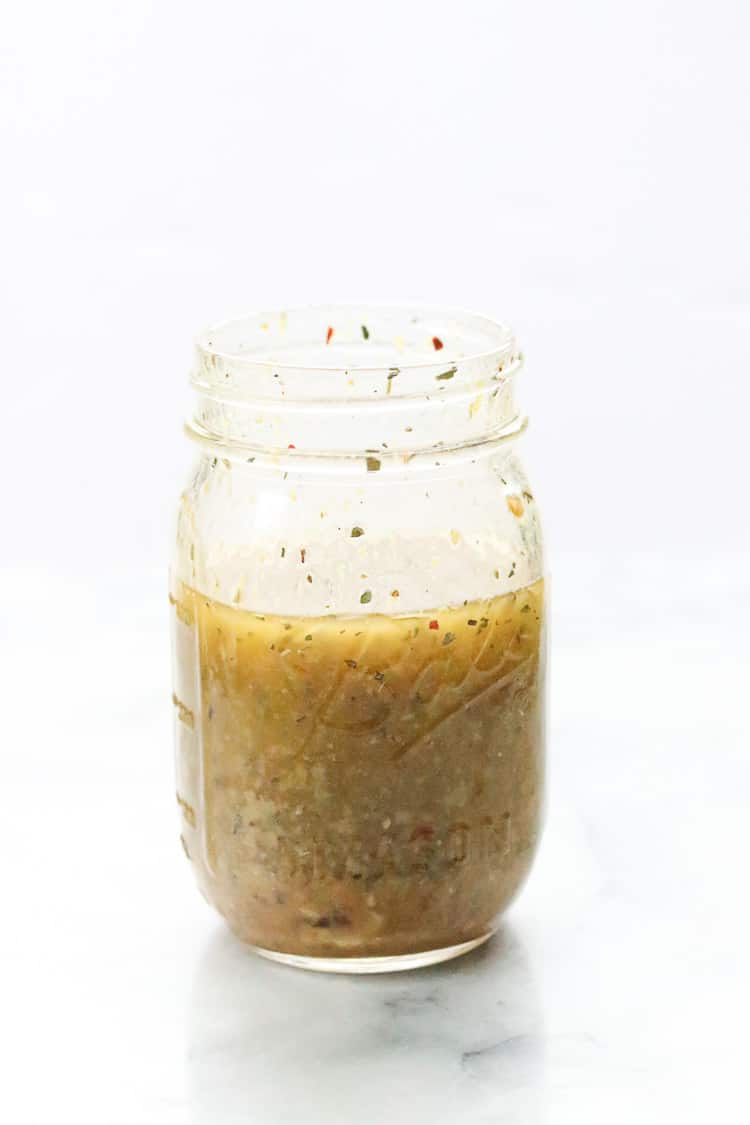 side shot of homemade Italian dressing ingredients mixed in a pint sized mason jar