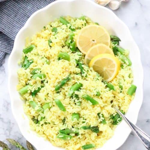 overhead shot of lemon rice in a white serving bowl with sliced lemons