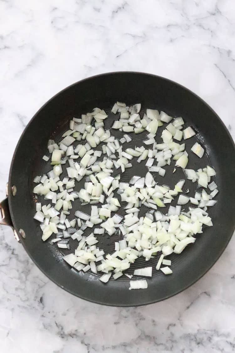 chopped white onion in black skillet for lemon rice recipe